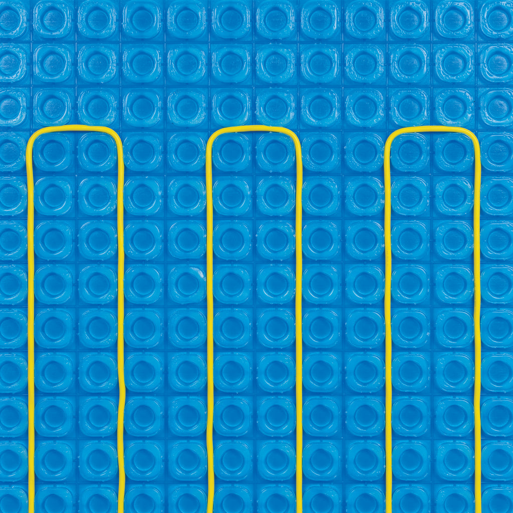 A close-up of a bright blue Thermosphere ultimate matting with a repeating circular pattern, overlaid with three vertical yellow heating cables.